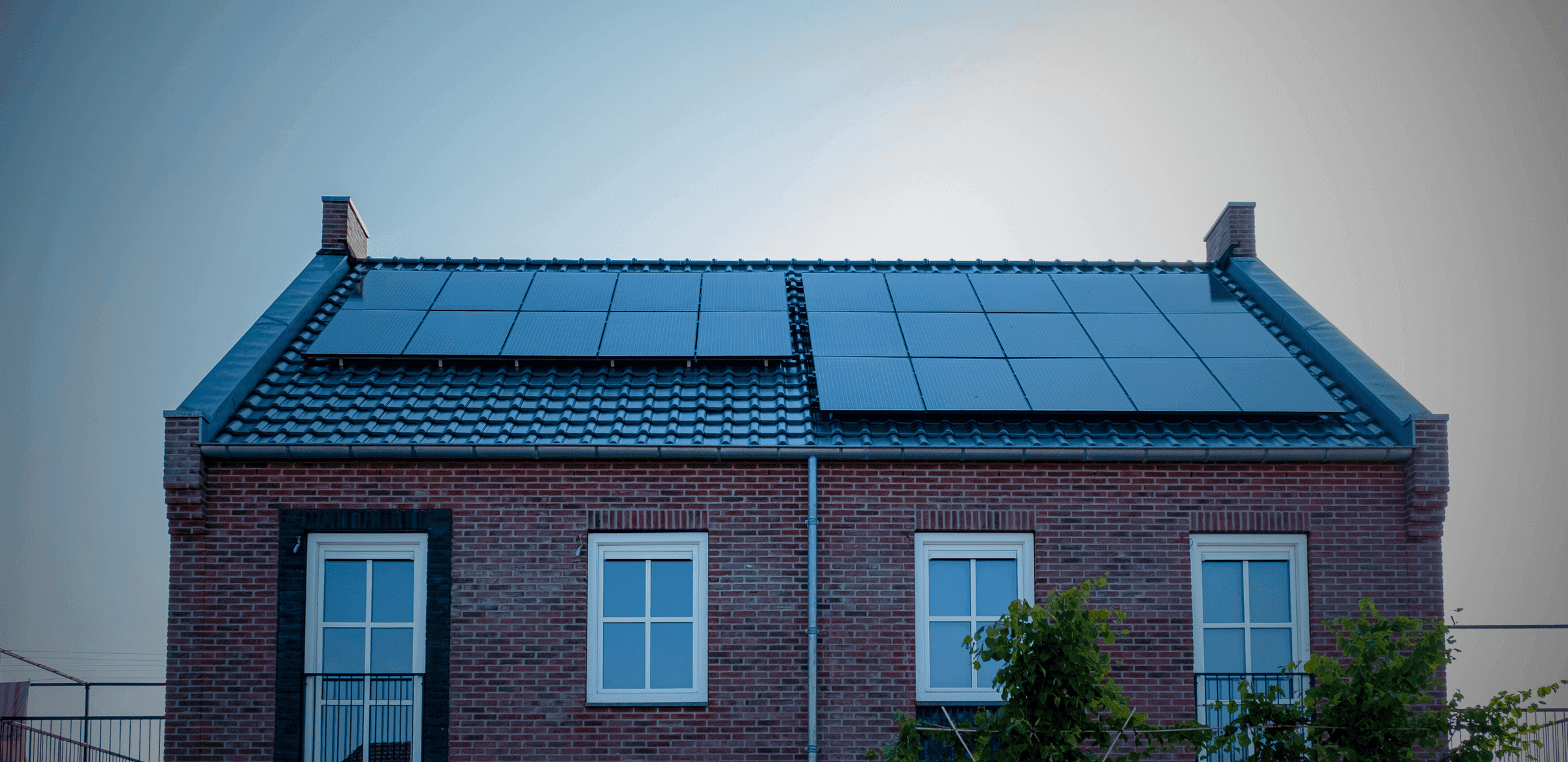 A brick house with a solar array across the main roof