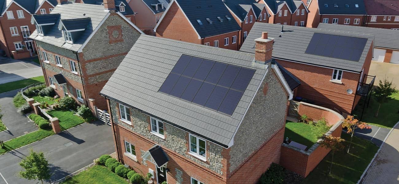 An in-roof solar array on a new brick and flint home, seen from above on a clear day